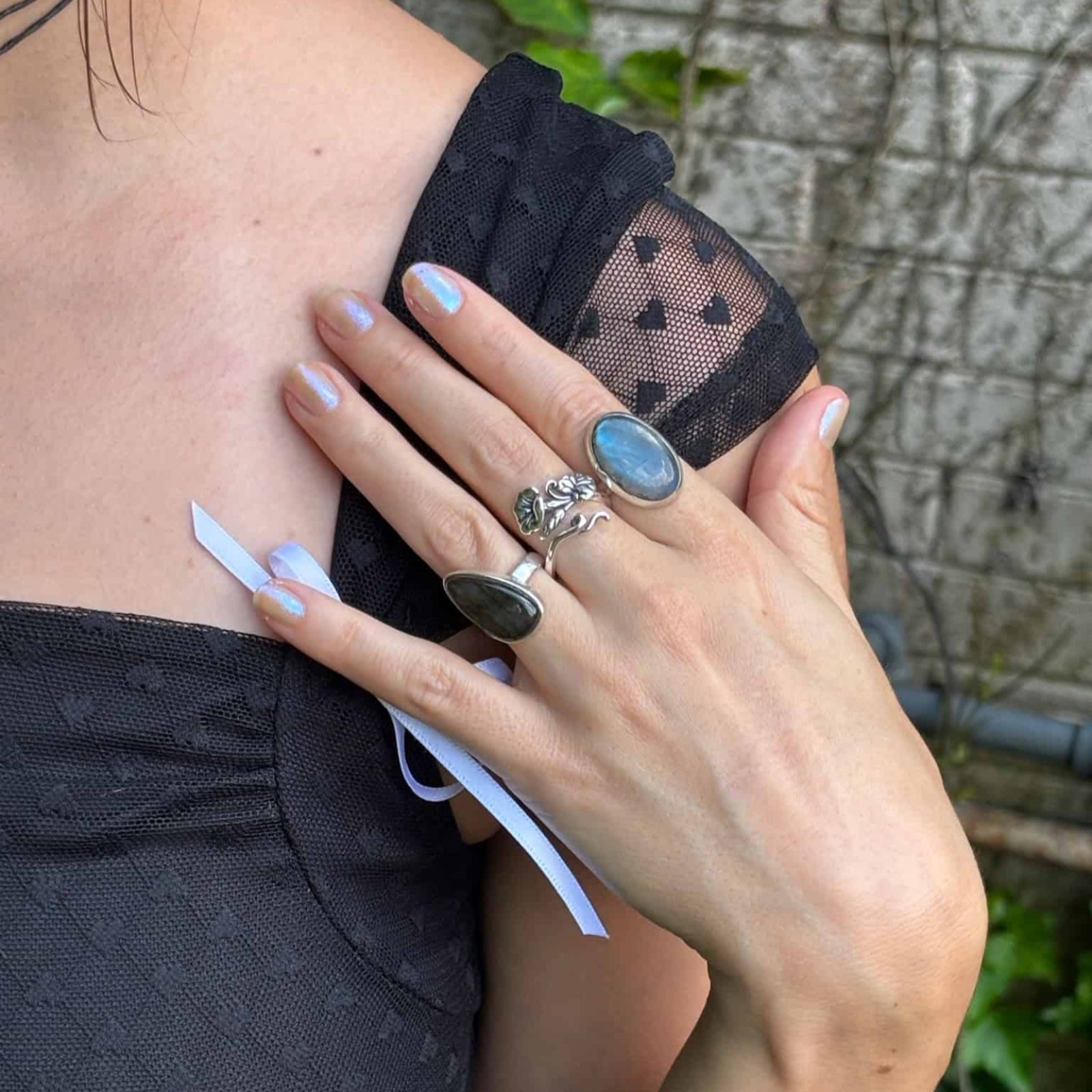 Person wearing a black top with sheer mesh details, holding a black fabric item.