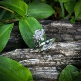 Silver rings on a wooden log with green leaves