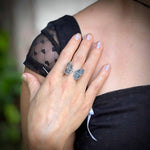 Person wearing a butterfly ring on a blurred natural background