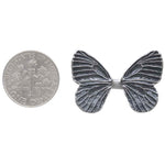 Butterfly-shaped object next to a U.S. dollar coin on a white background