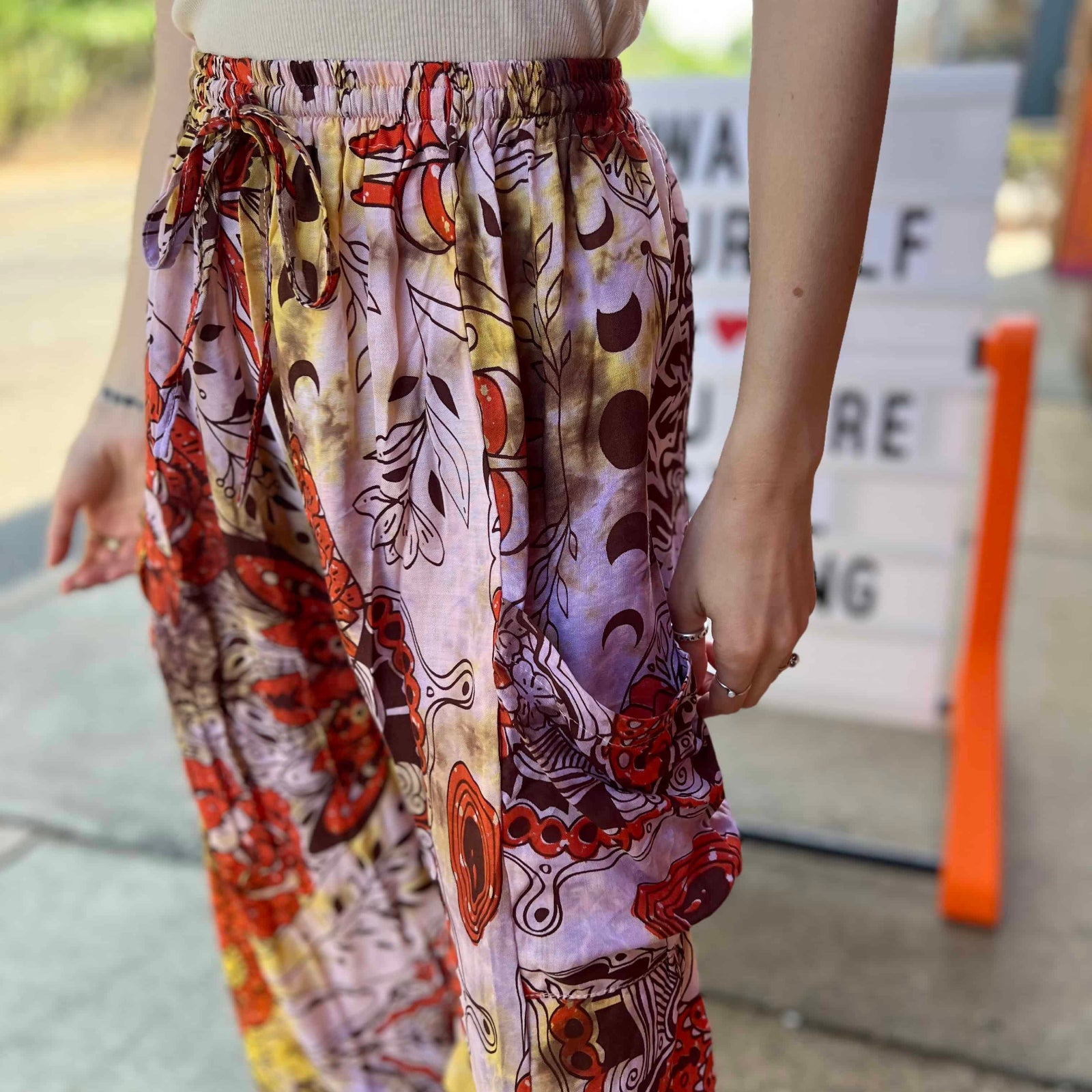 Model wearing red and purple tie-dye cargo pants with moon phase design