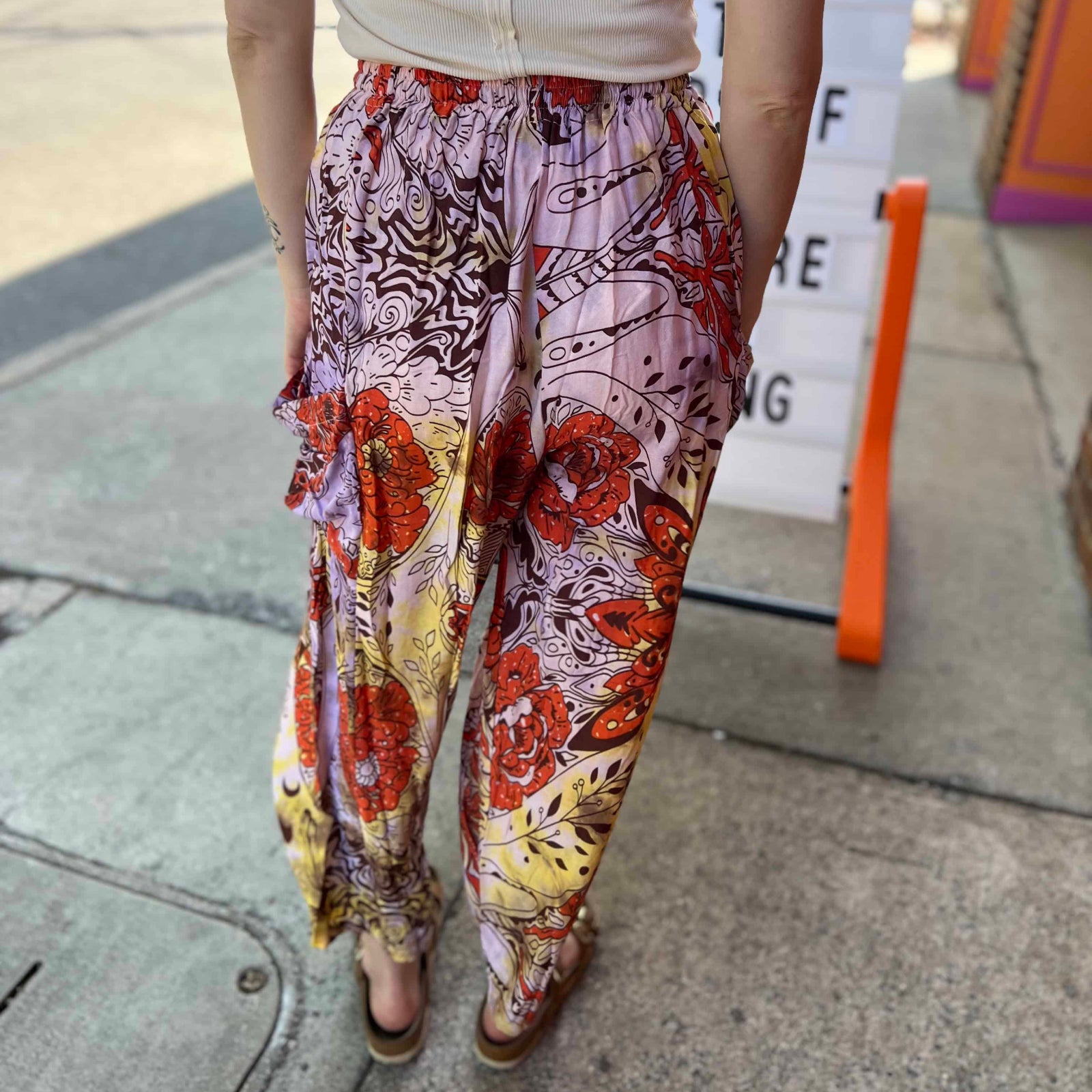 Model wearing red and purple tie-dye cargo pants with moon phase design back view of pants