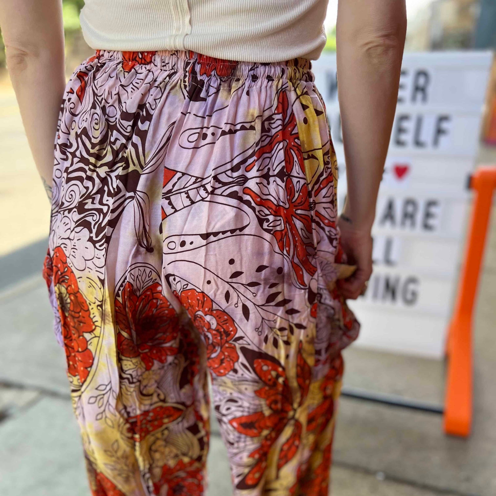 Model wearing red and purple tie-dye cargo pants with moon phase design close up view of back of pants
