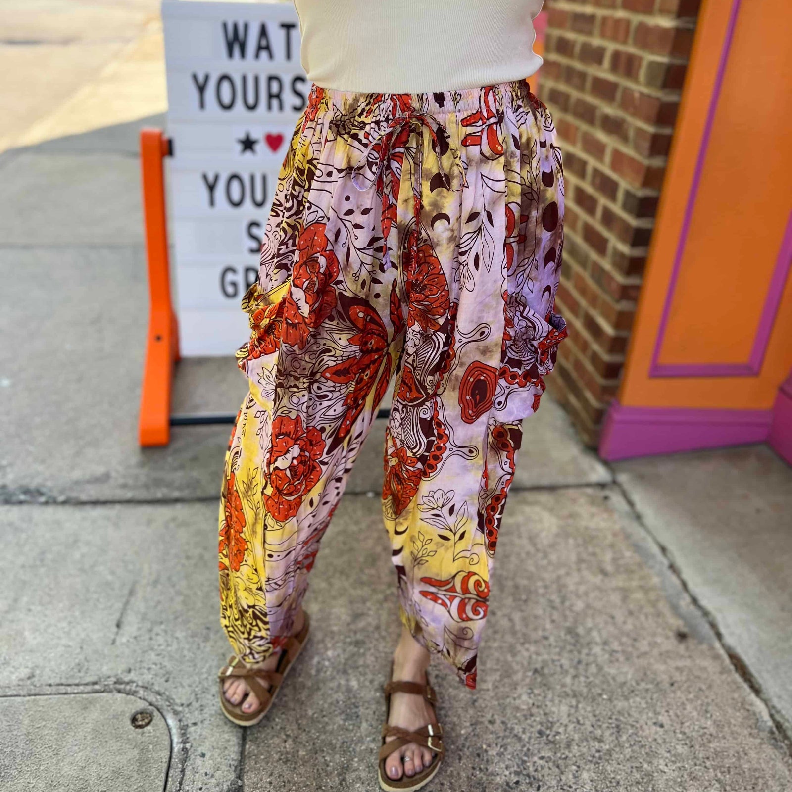 Model wearing red and purple tie-dye cargo pants with moon phase design view of legs and shoes