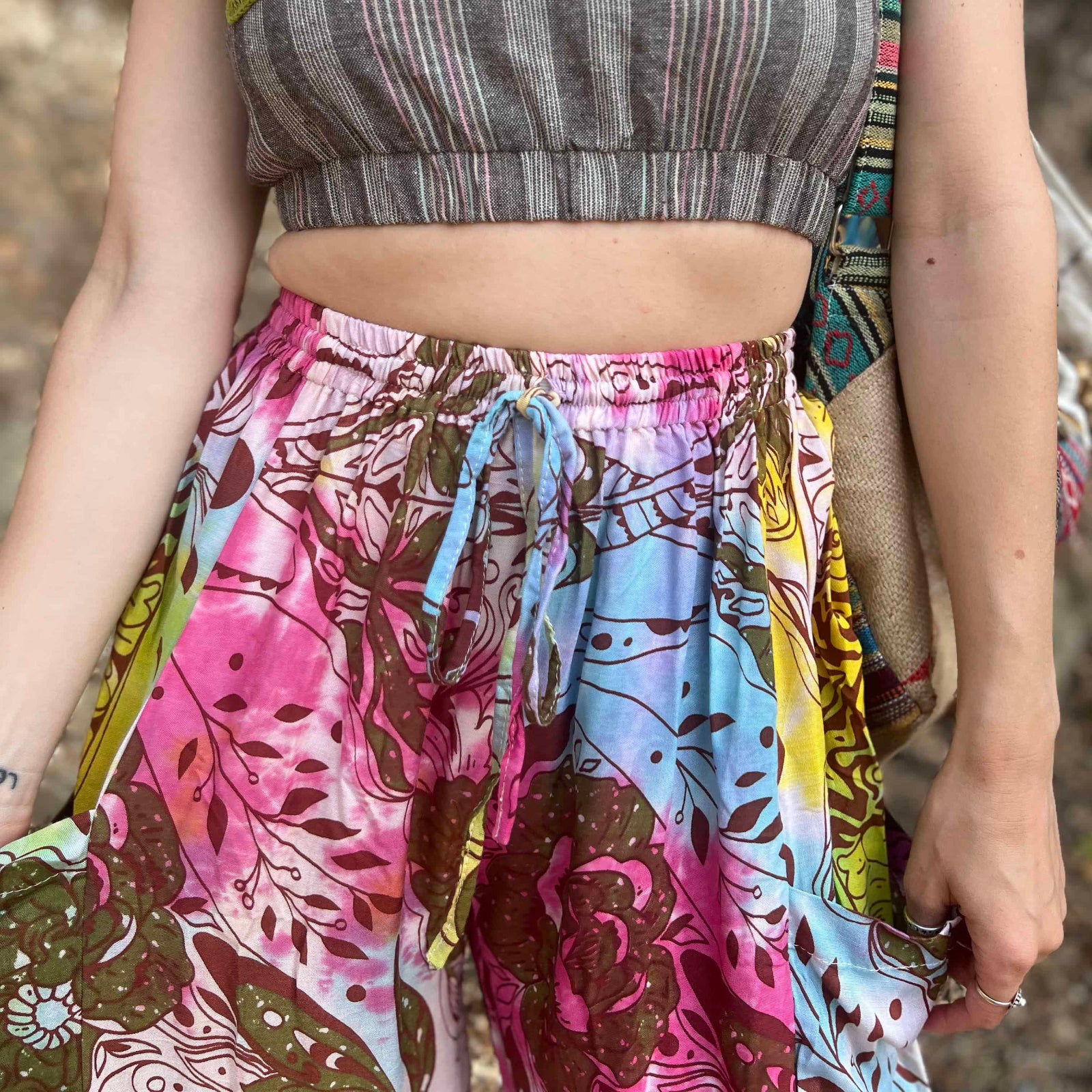 Rainbow tie-dye cargo pants with green floral moth pattern close up view showing midriff and crop top