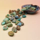 Turquoise stones with a decorative bowl on a beige background