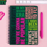 Wicked Notebook with motivational quote on a pink surface with keyboard and pen