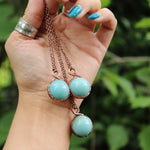 Hand holding three Amazonite crystal ball necklaces with copper chains