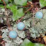 Close-up of Amazonite necklaces resting on moss and lichen-covered forest floor