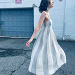 neutral toned striped midi dress styled with a trendy white city background