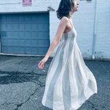 neutral toned striped midi dress styled with a trendy white city background
