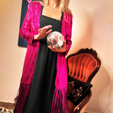 A woman wearing the Sequin Fringe Star Back Open Cardigan while holding a disco ball.