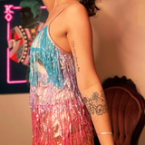 An up-close image of a woman wearing the Mini Disco Dress while holding a disco ball in front of a funky background, showing off the side.