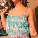 An up-close image of a woman wearing the Mini Disco Dress while holding a disco ball in front of a funky background.
