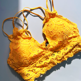 The mustard Criss-Cross Back Lace Bralette on a blue background.