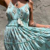 Mint green dress with intricate patterns and tassels against a stone wall background