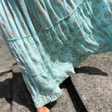 Light blue floral dress with ruffled layers on a concrete surface