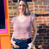 A woman wearing the mauve Boho Knit Sweater Crochet V-Neck Top with some denim pants.
