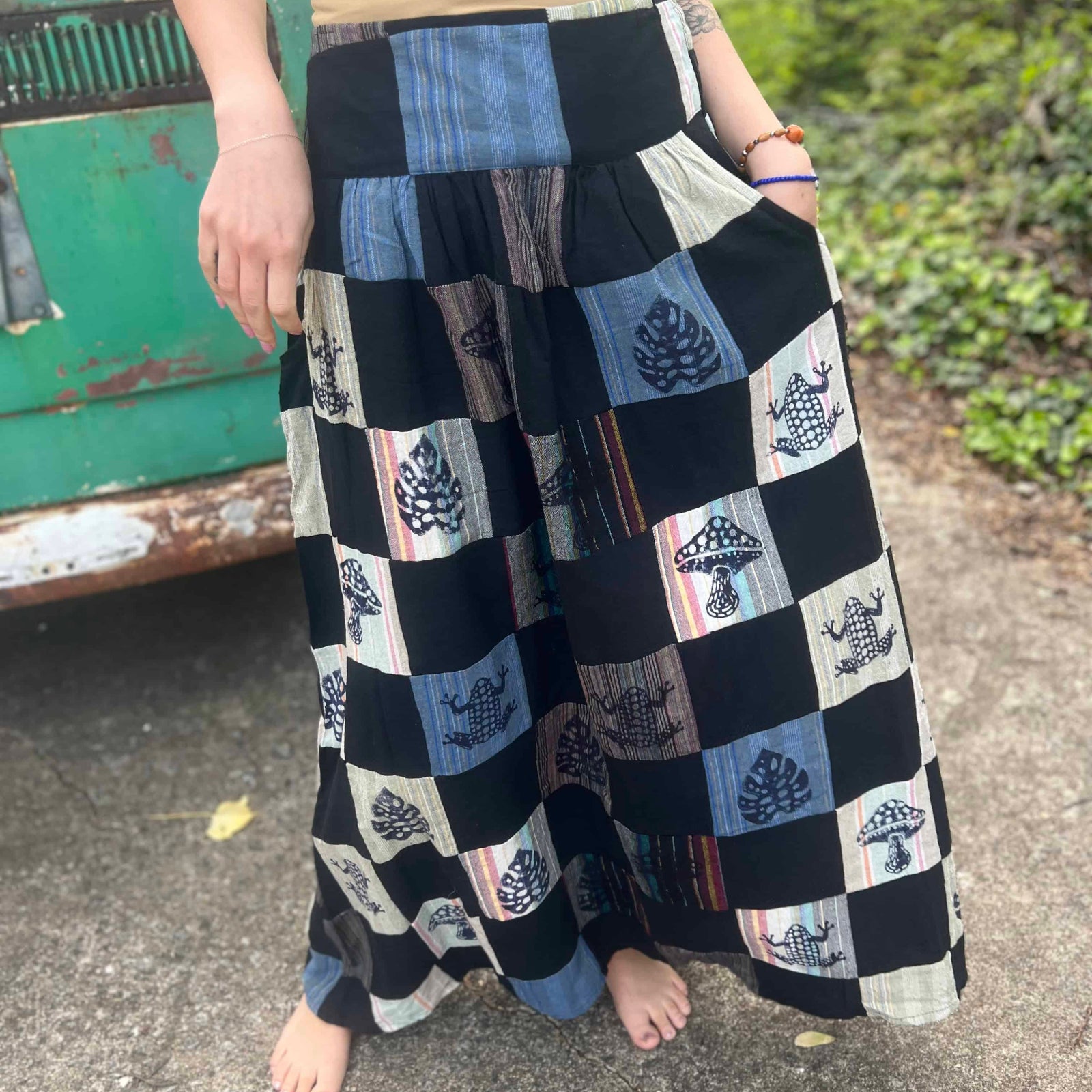 Woman wearing black patchwork boho maxi skirt with frog and mushroom designs close up view