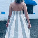 back view of bohemian striped midi dress against a white brick background