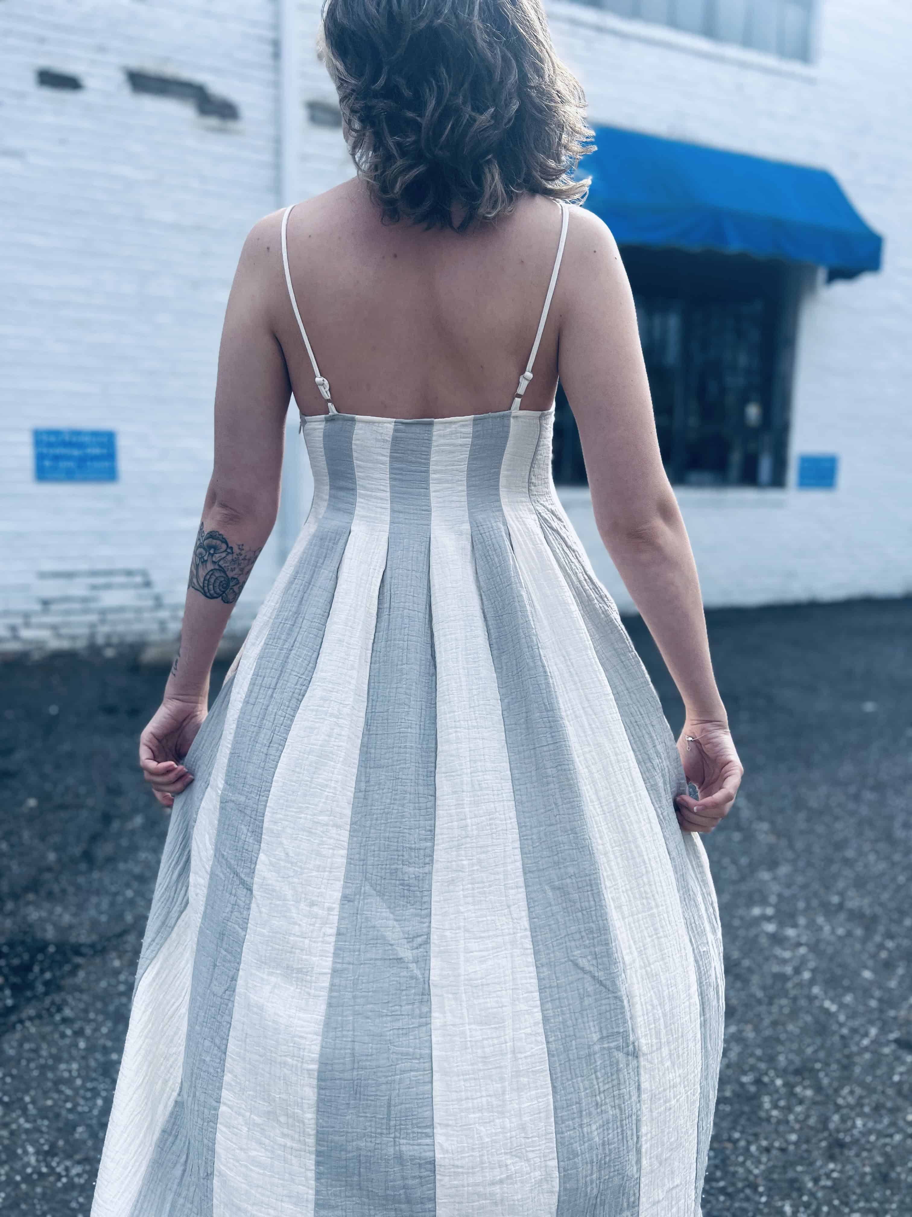 back view of bohemian striped midi dress against a white brick background