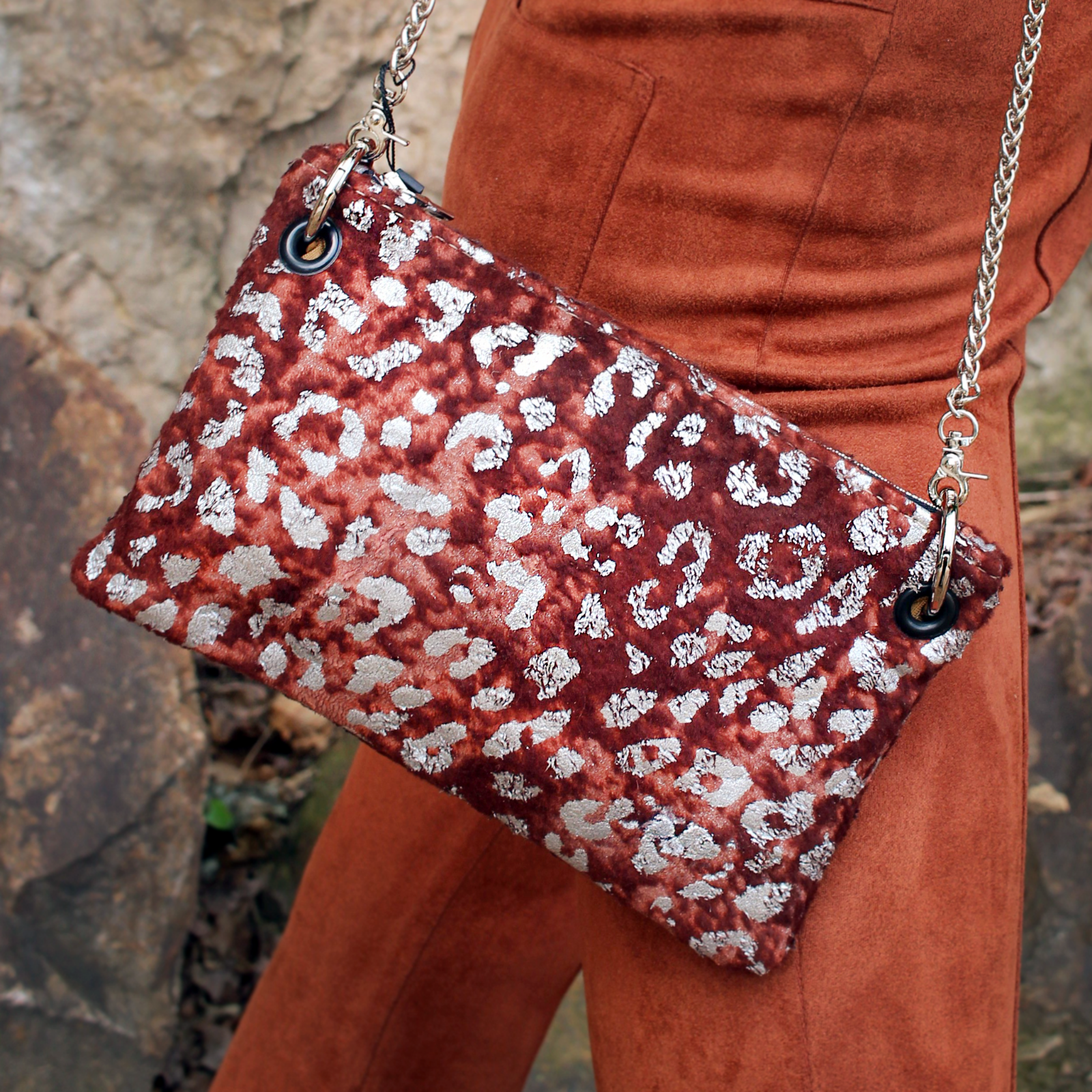 Someone wearing burnt orange pants is wearing the Garnet and Chrome Leopard Crossbody.