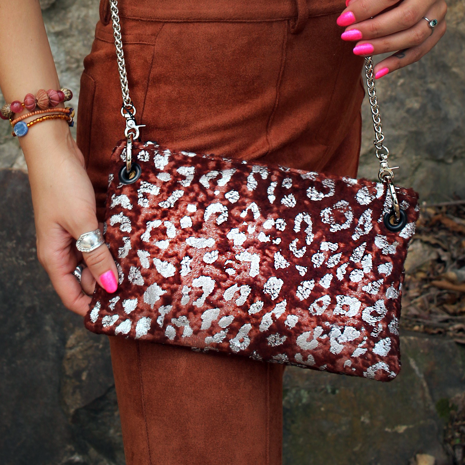 Someone wearing burnt orange pants is wearing the Garnet and Chrome Leopard Crossbody.