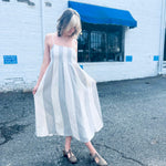 Boho-style striped cotton midi dress with pintuck details outside white brick wall