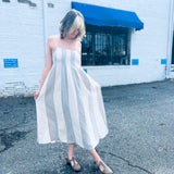 Boho-style striped cotton midi dress with pintuck details outside white brick wall