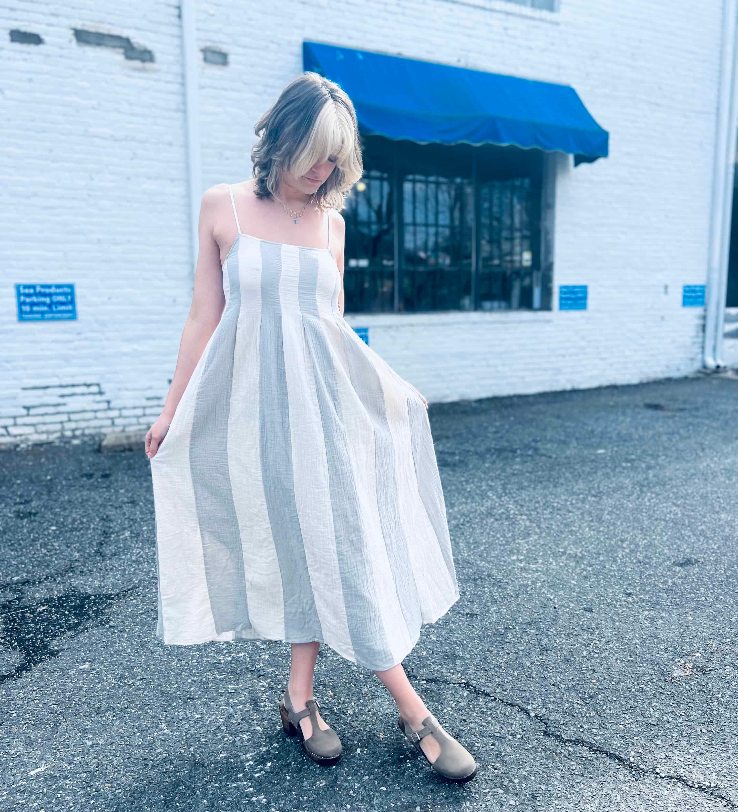 Boho-style striped cotton midi dress with pintuck details outside white brick wall
