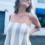 close up of pintuck details on sriped cotton gauze midi dress in front of white brick building