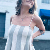 close up of pintuck details on sriped cotton gauze midi dress in front of white brick building