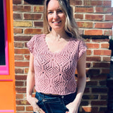 close up of a lightweight crochet knit detailing on a cotton v-neck cap sleeve top standing in front of the boho depot retail store