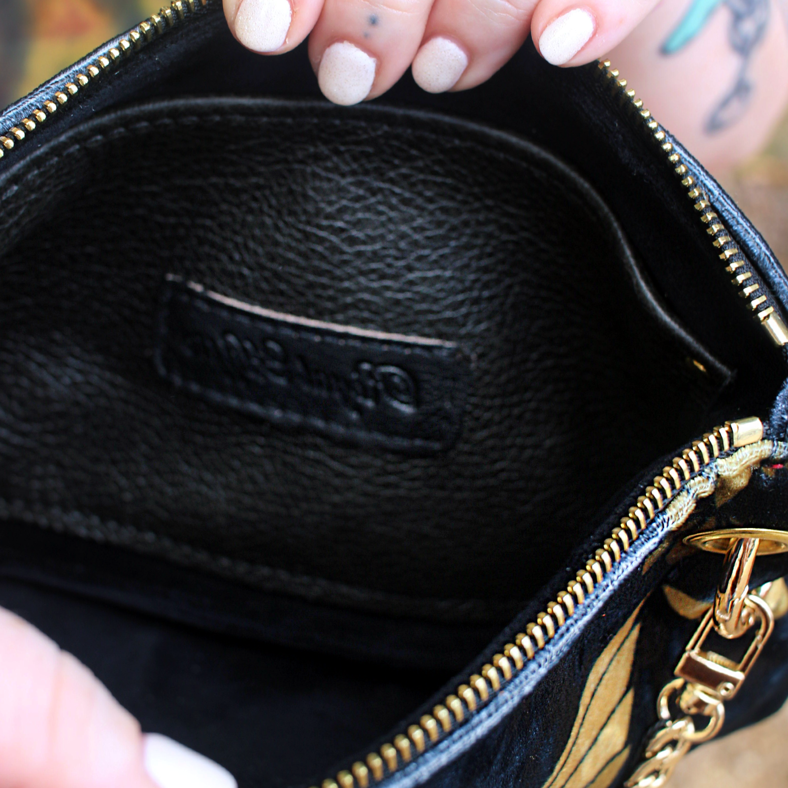 A woman holding the Black and Gold Heron Chain Strap Velvet Crossbody Bag open to show off the inside.