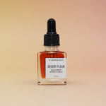 Bottle of 'Desert Fleur' perfume with a dropper on a beige background