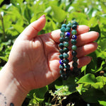 Hand holding Moss Agate evil eye bracelet outdoors