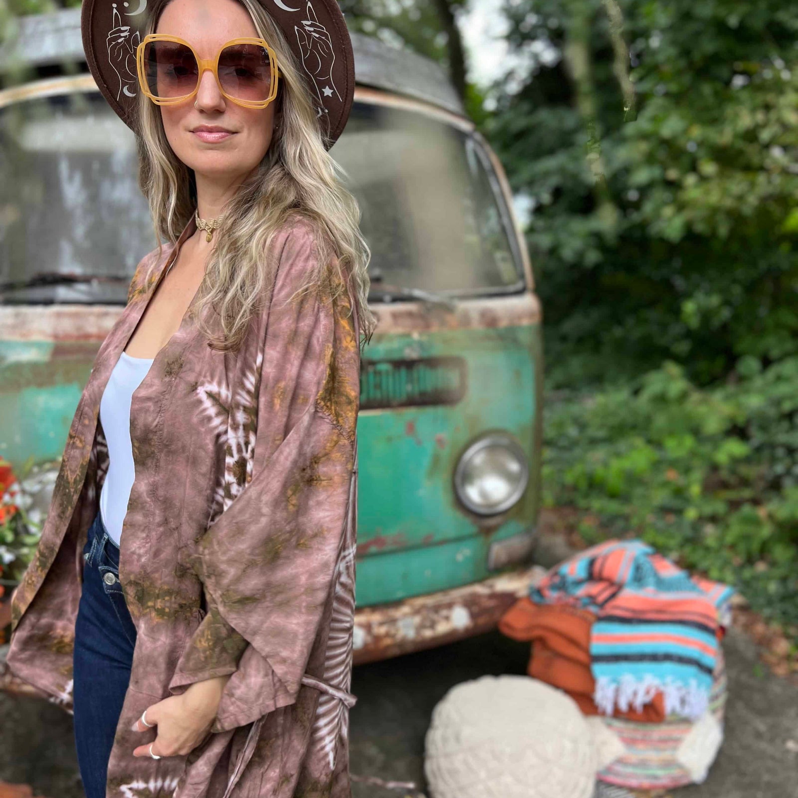 Woman in a patterned kimono standing in front of a vintage van with a relaxed outdoor setting.