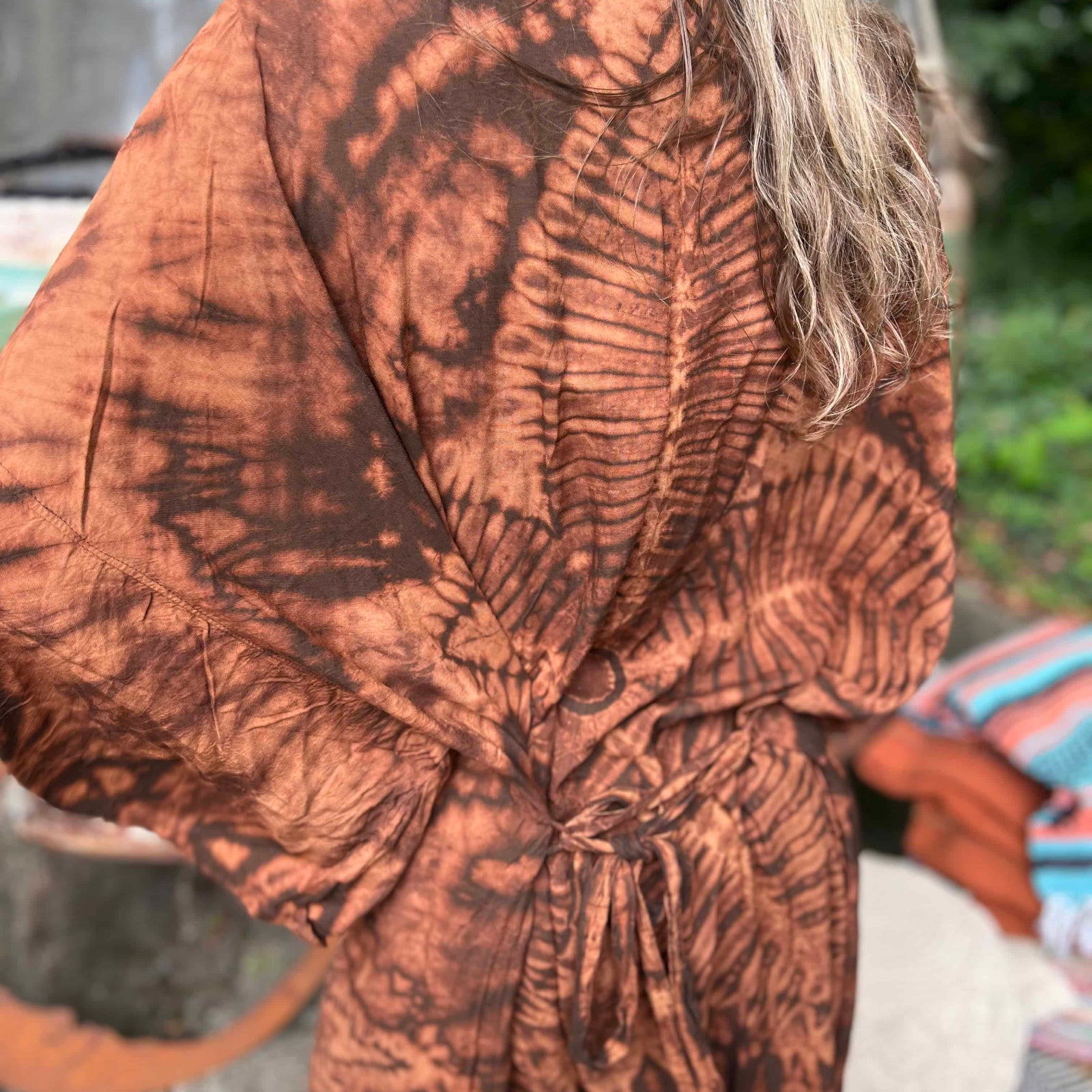 Person wearing a brown tie-dye kimono-style garment with blurred background