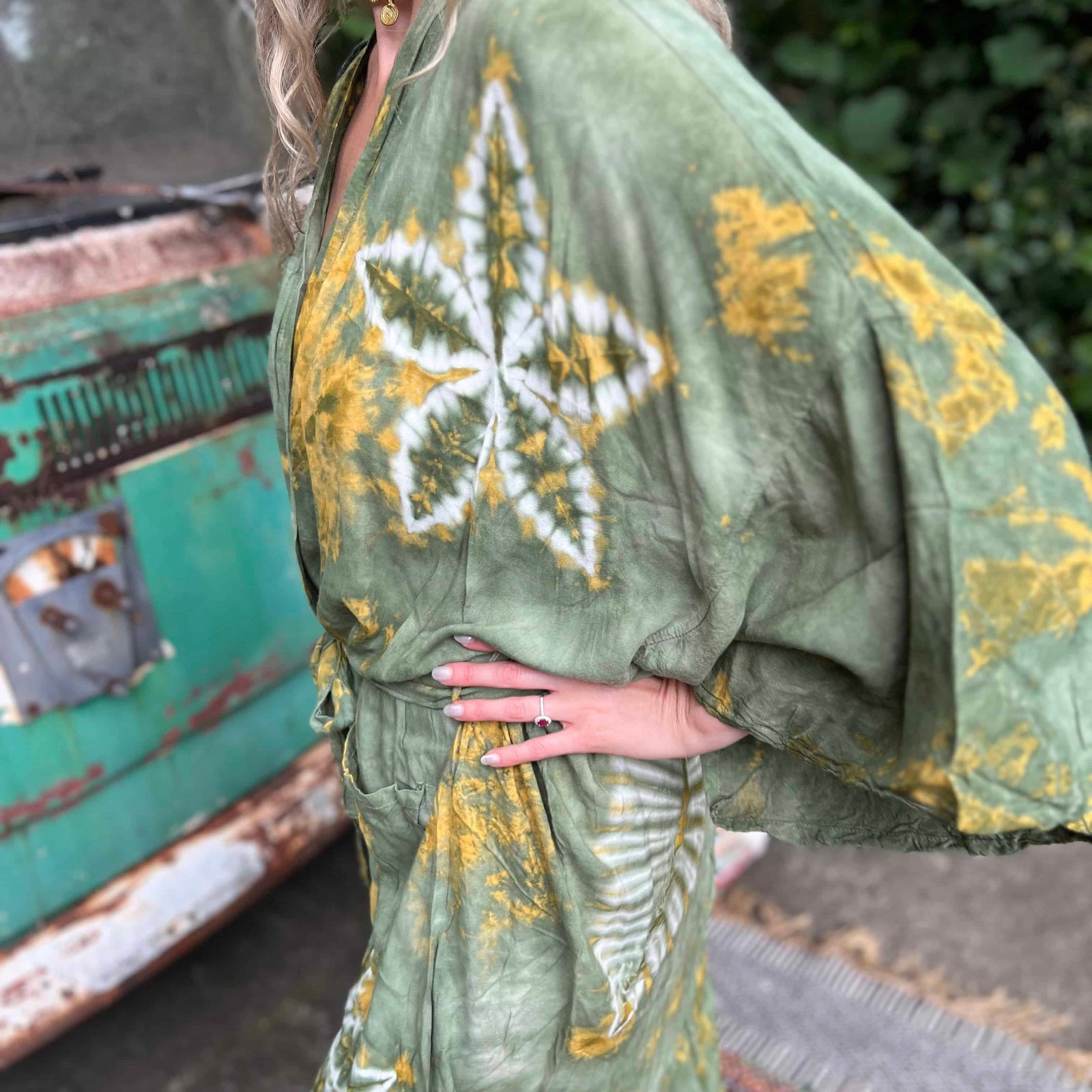 Person wearing a green and yellow tie-dye kimono with a blurred background
