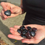 Person holding heart-shaped stones in their hands outdoors