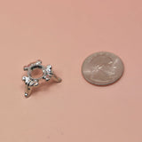 Silver sphere stand with decorative design next to a penny on a beige background