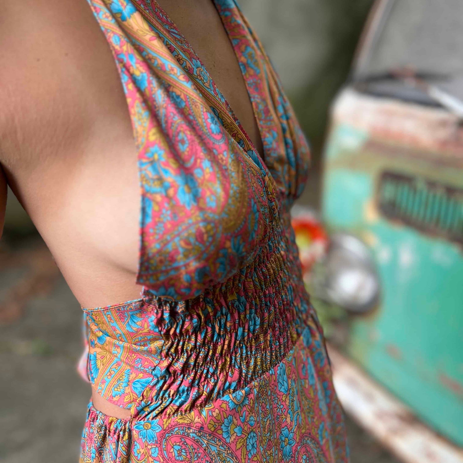 Woman wearing a colorful dress with fringe details, standing next to a vintage scooter.
