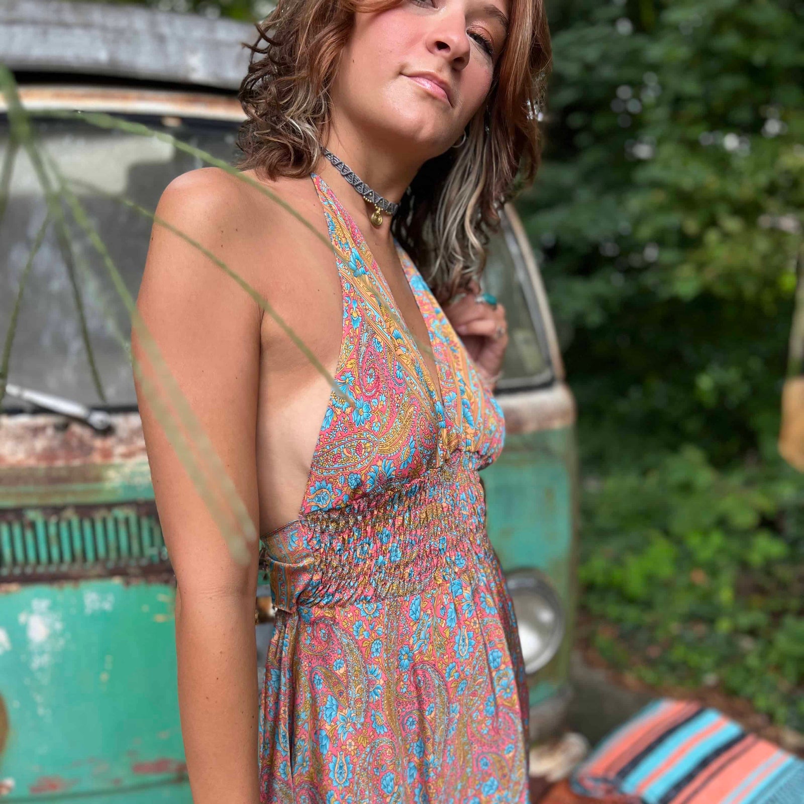 Woman wearing a floral dress with a vintage car and outdoor setting in the background