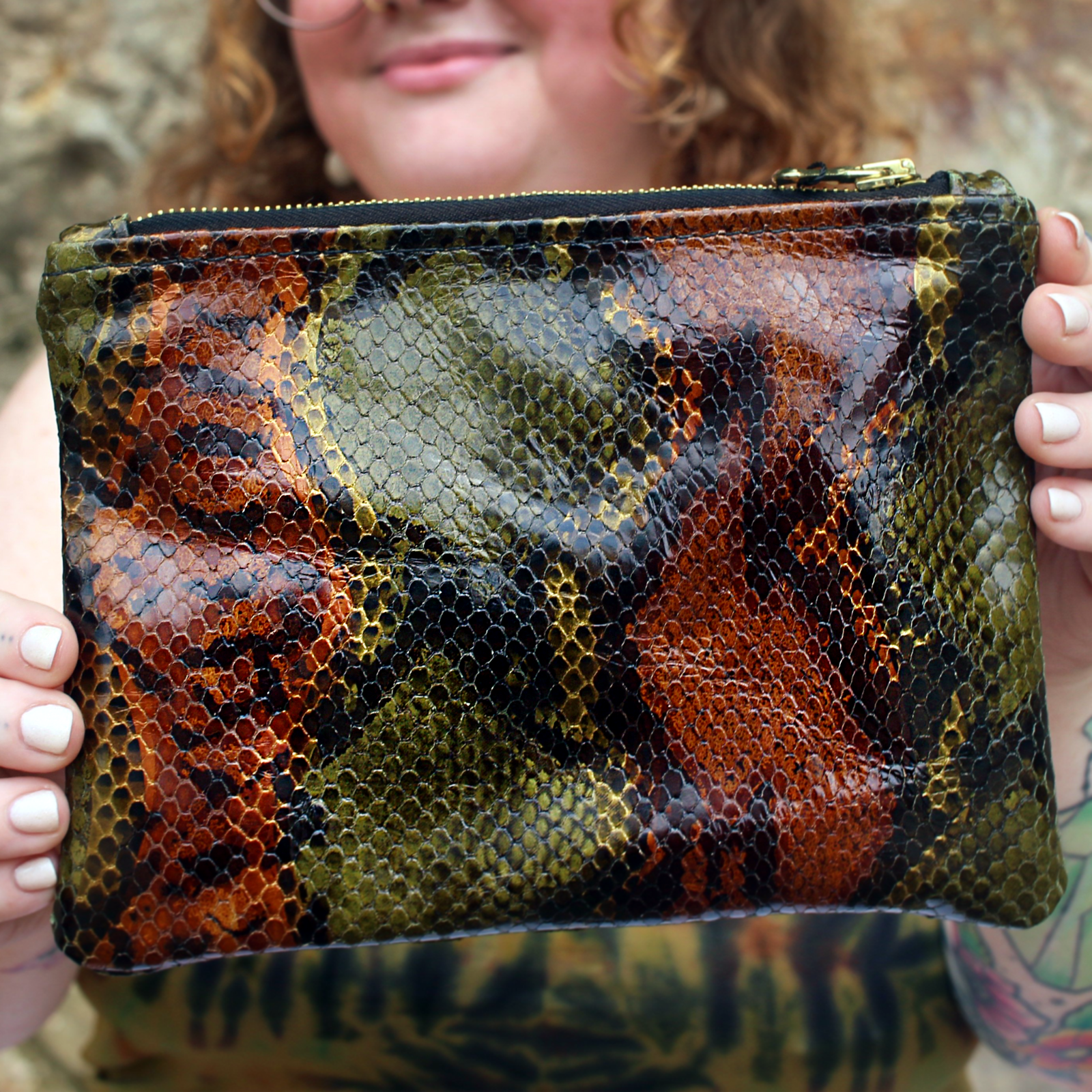 A woman holding the Bronze and Olive Snake Print Pouch showing the back.