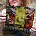 A woman holding the Bronze and Olive Snake Print Pouch.