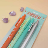 Set of pens with Taylor Swift Life of a 'Showgirl' branding on a pastel blue card against a beige background.