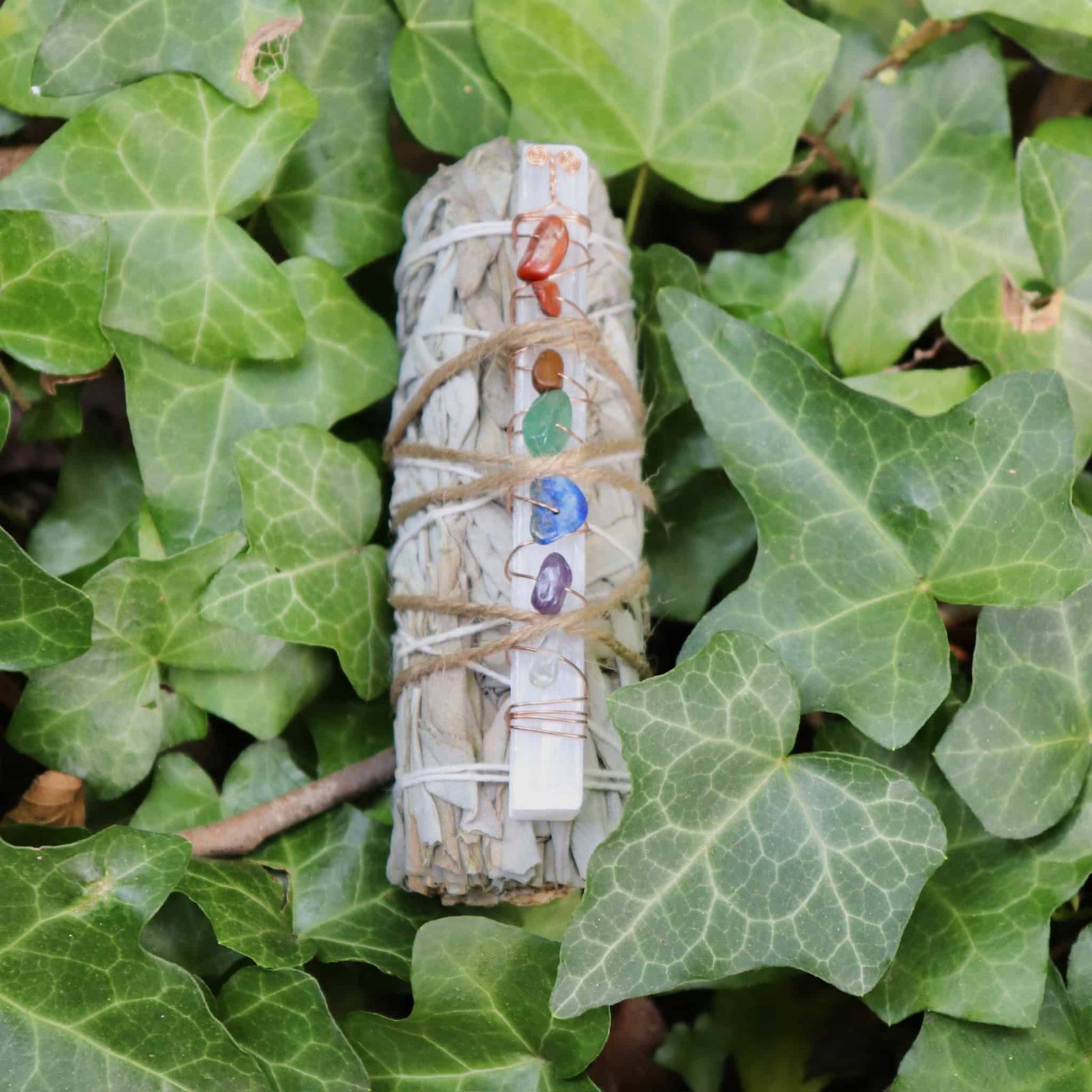 Bundled sage with colorful stones on green leaves