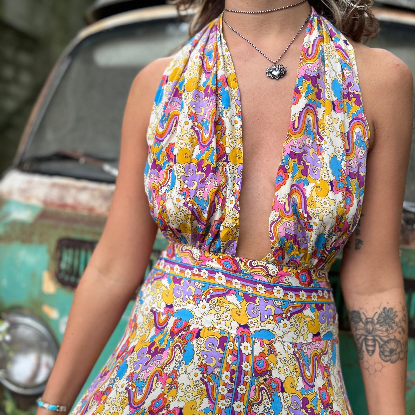 Woman wearing a colorful patterned dress with a vintage vehicle in the background