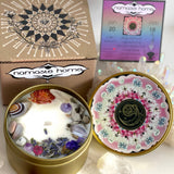 The Aquarius Crystal Candle opened with the lid to the right of it. The packaging of the Aquarius Crystal Candle is behind the candle next to an Aquarius info card.