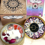 The Sagitarius Crystal Candle opened with the lid to the right of it. The packaging of the Saggitarius Crystal Candle is behind the candle next to a card.